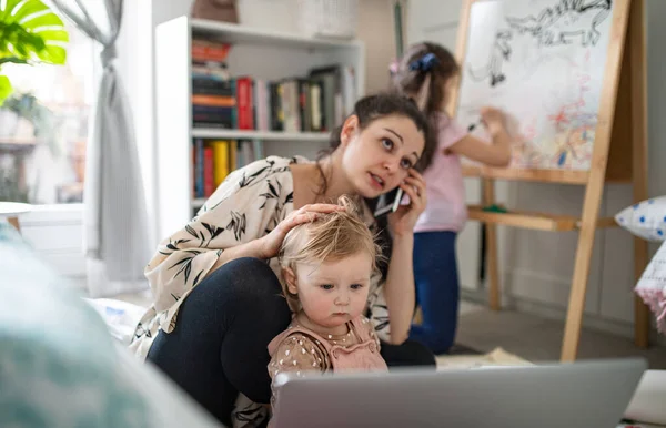 Moeder werken met kleine dochters in de slaapkamer, home office concept. — Stockfoto