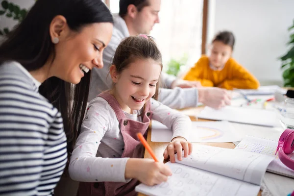 Föräldrar med skolflickor inomhus, distansundervisning. — Stockfoto