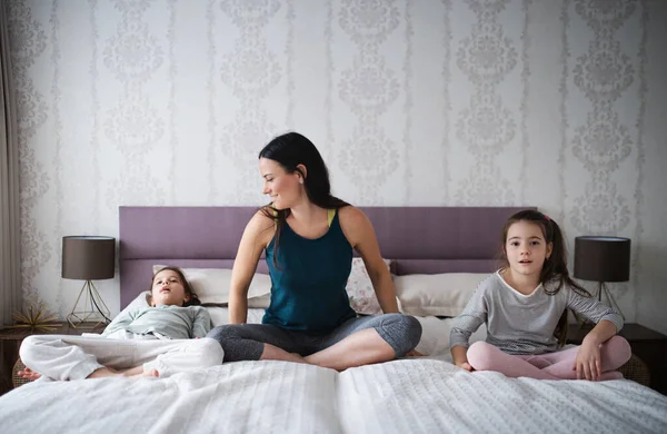 Mãe com filhas na cama após o exercício em casa. — Fotografia de Stock