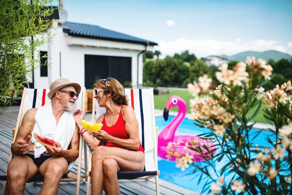 Весела старша пара сидить біля басейну на відкритому повітрі на подвір'ї . — стокове фото