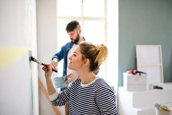 Mid adultos casal pintura parede dentro de casa, realocação e diy conceito. — Fotografia de Stock