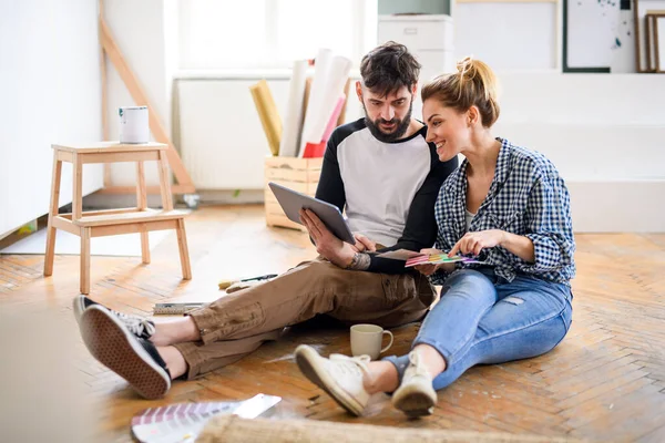 Mediados de adultos pareja planeando con la tableta en el interior de casa, reubicación y concepto de bricolaje. — Foto de Stock