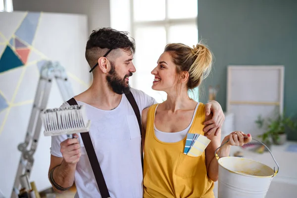 Pareja divirtiéndose al pintar paredes interiores en casa, reubicación y concepto de bricolaje. — Foto de Stock