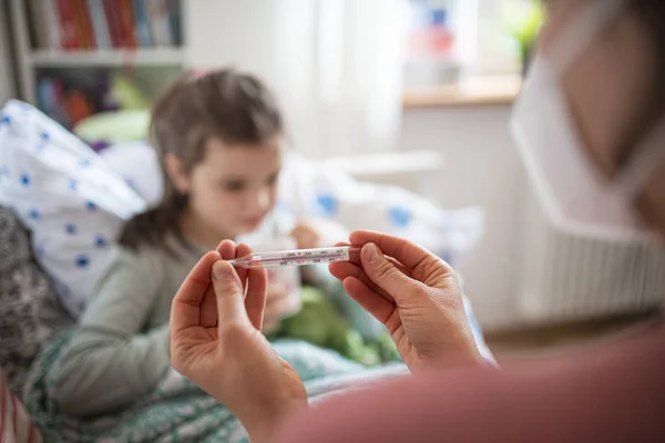 Mother looking after sick small daughter in bed at home. — Stock Photo, Image