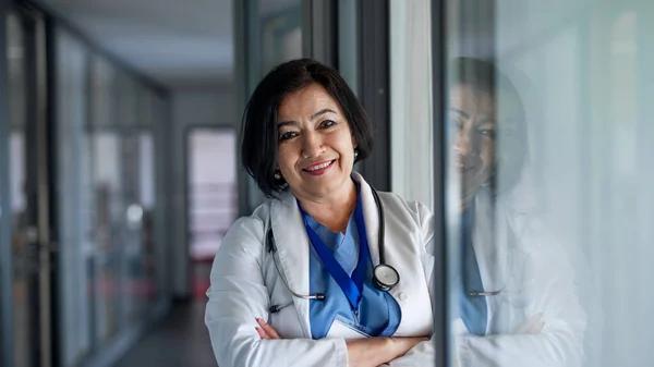 Porträt einer Oberärztin, die im Krankenhaus steht und in die Kamera blickt. — Stockfoto