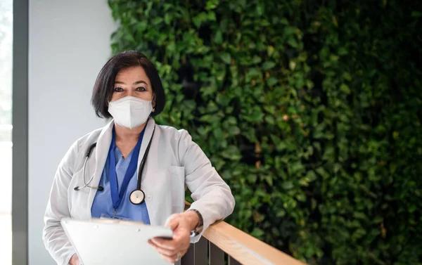 Retrato de la mujer mayor médico de pie en el hospital y mirando a la cámara, concepto de coronavirus. — Foto de Stock