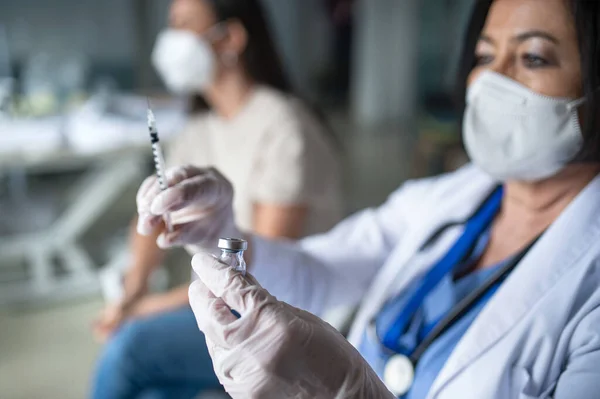 Oudere vrouwelijke arts met injectiespuit in ziekenhuis, coronavirus en vaccinatie concept. — Stockfoto