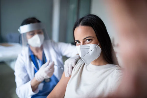 Vrouw met gezichtsmasker die wordt gevaccineerd en selfie inneemt in het ziekenhuis, coronavirus en vaccinatieconcept. — Stockfoto