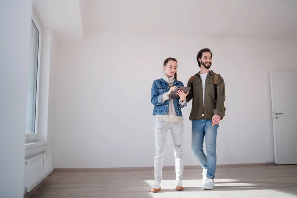 Pareja joven con tableta moviéndose y planeando en nuevo plano, nuevo hogar y concepto de reubicación. — Foto de Stock