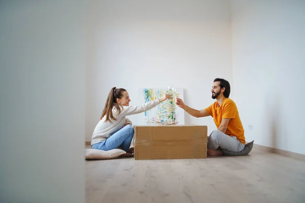 Pareja joven con cajas y vino moviéndose en nuevo piso, nuevo hogar y concepto de reubicación. — Foto de Stock