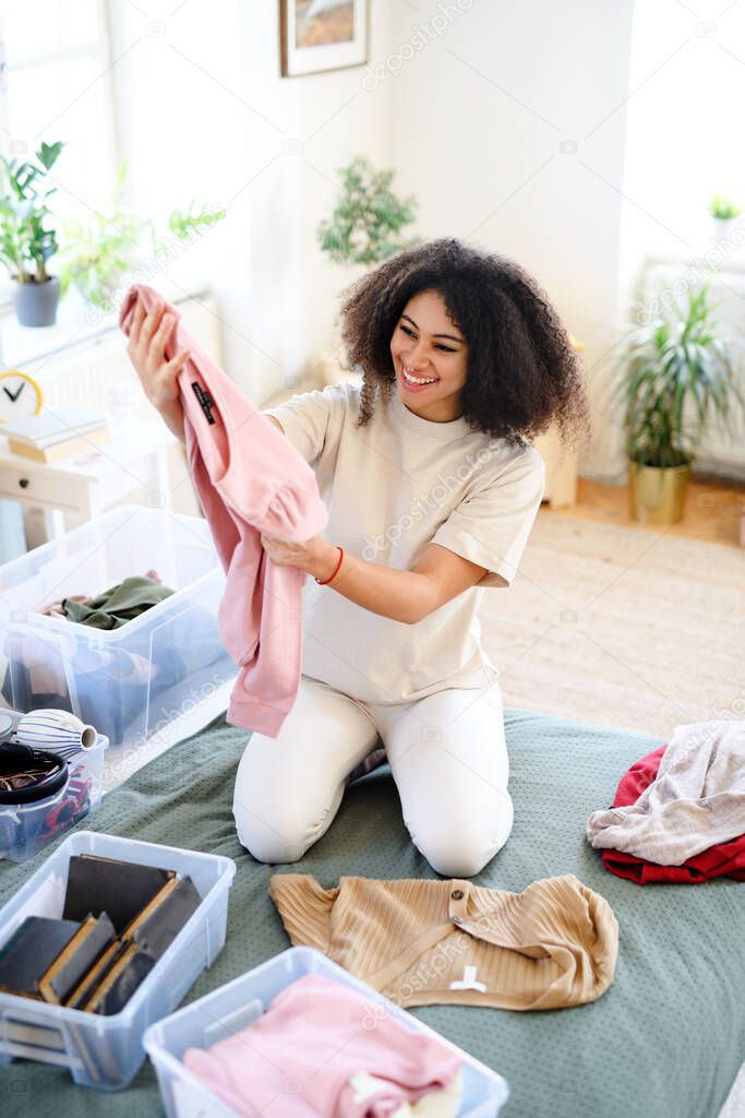 Young woman sorting wardrobe indoors at home, charity donation concept.
