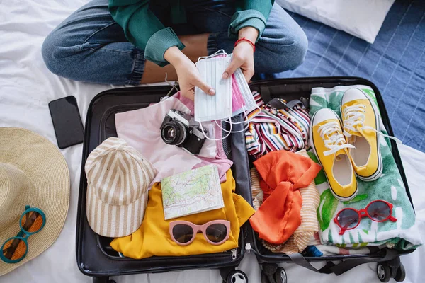 Mujer irreconocible con maleta de embalaje para vacaciones en casa, concepto coronavirus. — Foto de Stock