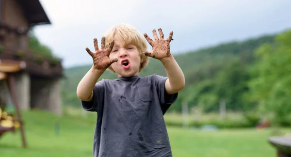 Small boy with dirty hands standing in vegetable garden, sustainable lifestyle. — Stock Photo, Image