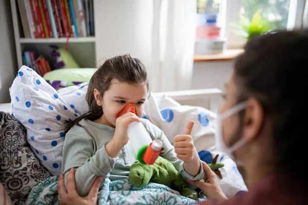 Mutter und kranke kleine Tochter mit Inhalator im Bett zu Hause, Coronavirus-Konzept. — Stockfoto