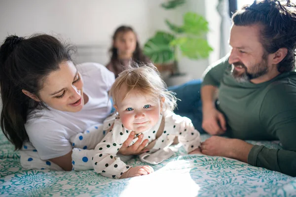 Gezin met twee kleine dochters die plezier hebben op bed thuis. — Stockfoto