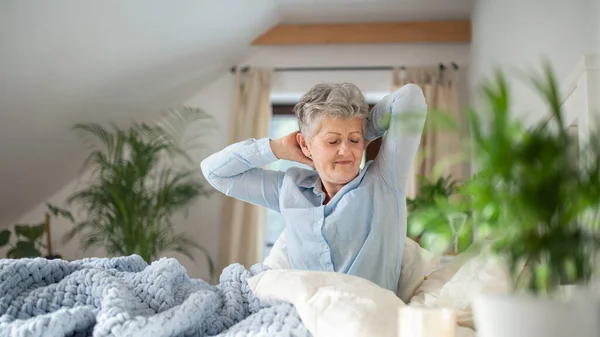 Seniorin im Bett zu Hause morgens aufstehen. — Stockfoto