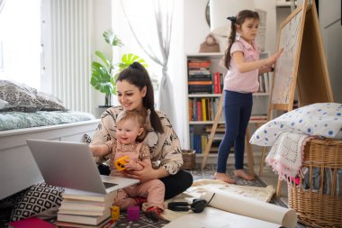 Anne yatak odasında küçük kızlarla çalışıyor, ev ofis konsepti..