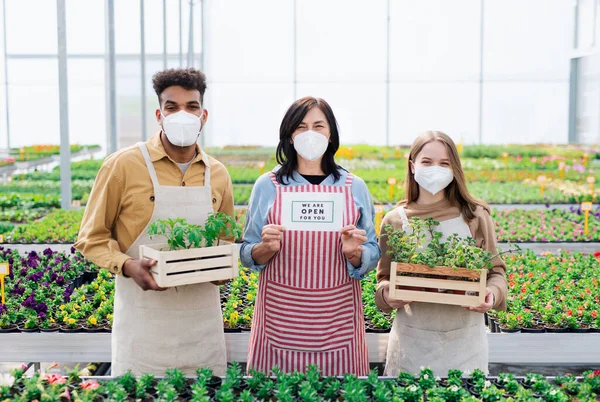 Personas que trabajan en invernadero en el centro de jardinería, tienda abierta después del cierre del coronavirus. — Foto de Stock