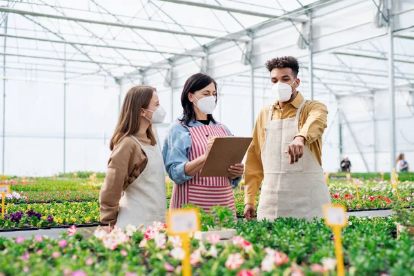 Personas que trabajan en invernadero en el centro de jardinería, concepto coronavirus. — Foto de Stock