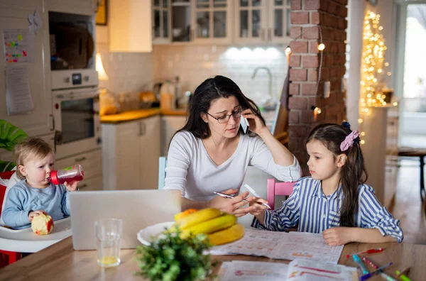 Mother with small daughter in kitchen, home schooling, office and distance learning concept. — Stock Photo, Image