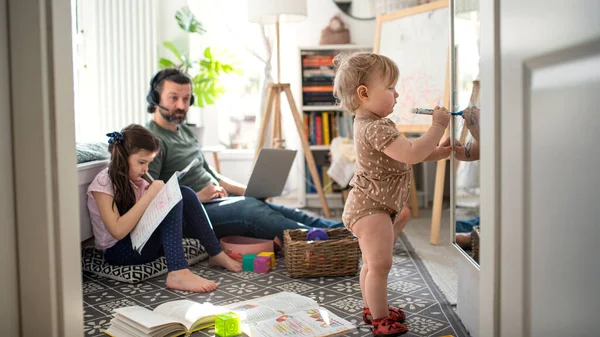 Ayah bekerja dengan anak-anak kecil di kamar tidur, konsep kantor rumah. — Stok Foto