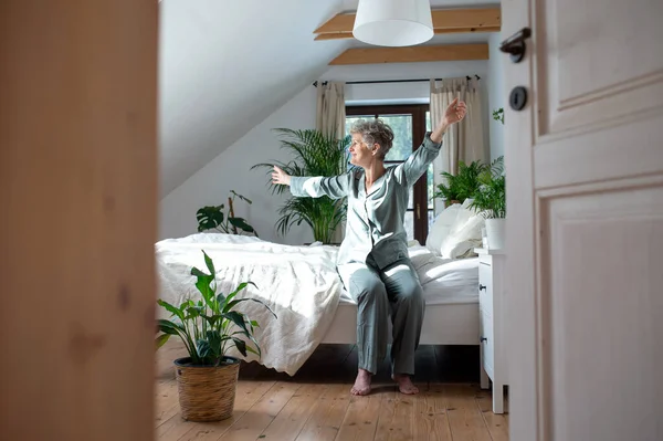 Senior kvinna i sängen hemma stiger upp på morgonen. — Stockfoto