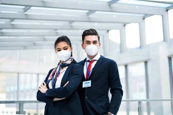 Young flight attendants looking at camera in airport lounge, coronavirus, travel and new normal. — Stock Photo, Image