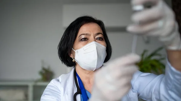 병원에서 주사기를 들고 있는 선임 여성 의사의 모습, 코로나 바이러스 개념. — 스톡 사진