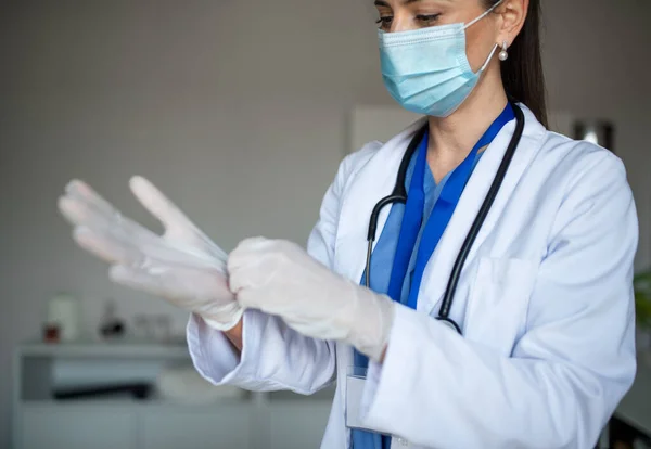 Portret van een vrouwelijke arts die handschoenen aantrekt in het ziekenhuis, coronavirus concept. — Stockfoto