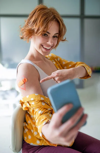 Mulher feliz com gesso no braço após a vacinação no hospital, tomando selfie. — Fotografia de Stock