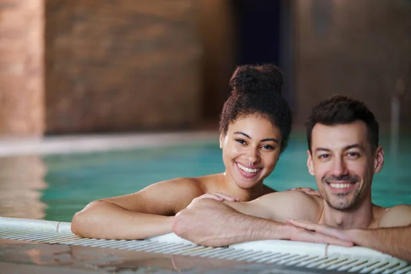 Retrato de jovem casal na piscina, olhando para a câmera. — Fotografia de Stock