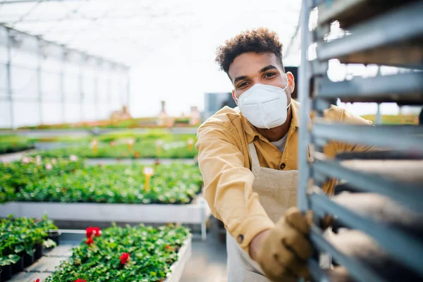 Joven trabajando en invernadero en el centro de jardinería, concepto coronavirus. — Foto de Stock