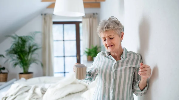 Mujer mayor en la cama en casa levantándose por la mañana. — Foto de Stock