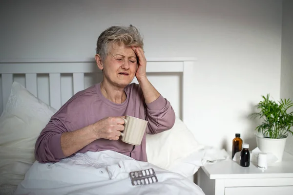 Wanita senior yang sakit di tempat tidur di rumah, sakit kepala dan konsep penyakit. — Stok Foto