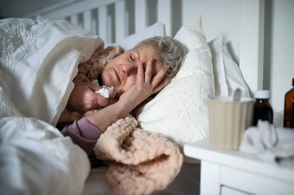 Zieke oudere vrouw slapen in bed thuis, koud en griep concept. — Stockfoto