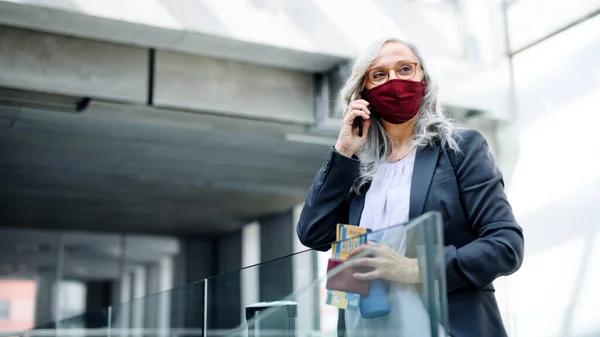 Senior žena s chytrým telefonem v letištní hale, coronavirus, cestování a nové normální. — Stock fotografie