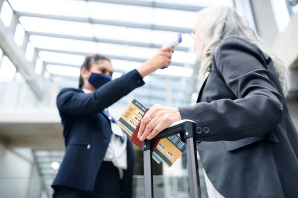 Seniorin im Flughafenterminal, Coronavirus, Reisen, Temperaturmessung und neue Normalität. — Stockfoto