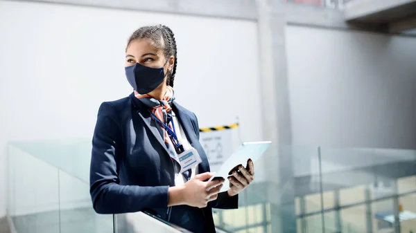 Young air hostess with tablet in airport lounge, coronavirus, travel and new normal. — Stock Photo, Image