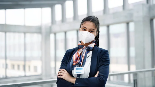 Young air hostess looking at camera in airport lounge, coronavirus, travel and new normal. — Stock Photo, Image