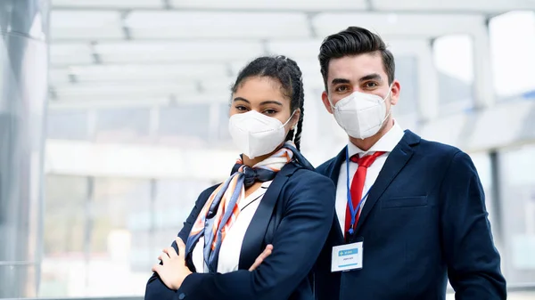 Young flight attendants looking at camera in airport lounge, coronavirus, travel and new normal. — Stock Photo, Image