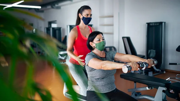 Mulher sênior com personal trainer fazendo exercício no ginásio, conceito de coronavírus. — Fotografia de Stock