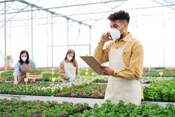 Personas que trabajan en invernadero en el centro de jardinería, concepto coronavirus. — Foto de Stock