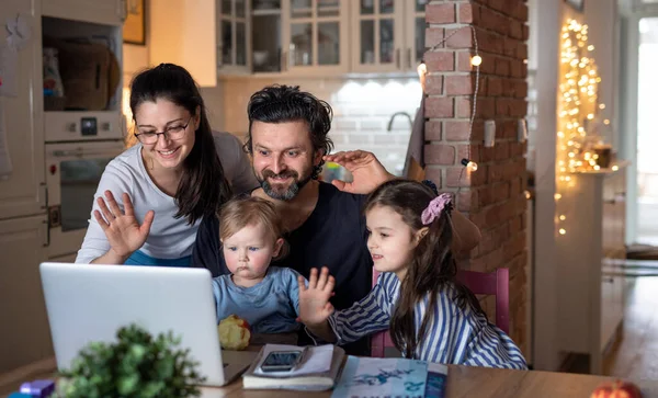 Gezin met kleine dochters in keuken, afstandsonderwijs, videogesprek met familie of vrienden. — Stockfoto