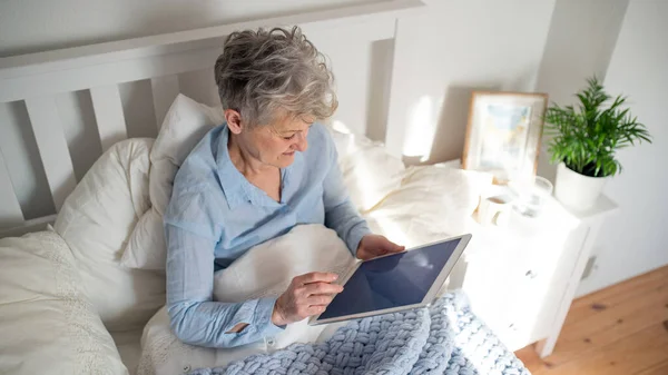 Happy senior woman using tablet in bed at home. — Stock Photo, Image