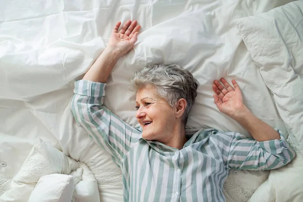 Vista dall'alto della felice donna anziana a letto a casa, rilassante. — Foto Stock