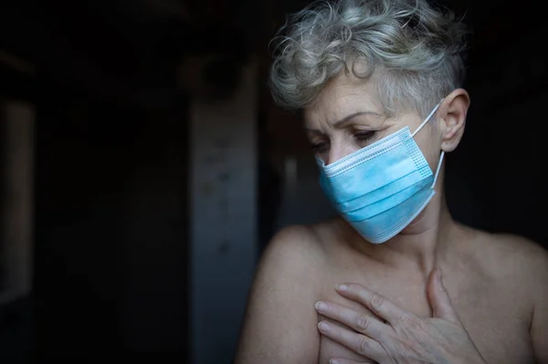 Mulher idosa deprimida com máscara facial em casa, coronavírus e conceito de saúde mental. — Fotografia de Stock
