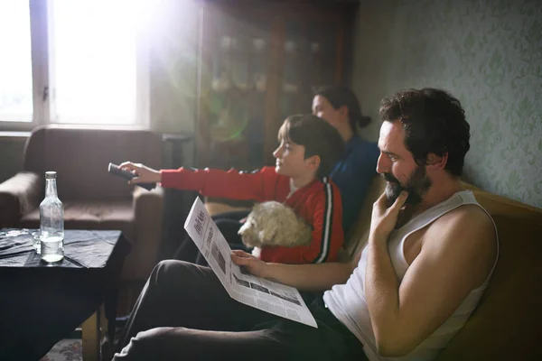 Retrato de pareja adulta pobre con hija pequeña viendo televisión en casa, concepto de pobreza. —  Fotos de Stock