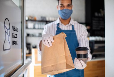 Garson siparişi hazırlıyor, kameraya bakıyor. Coronavirus konsepti.