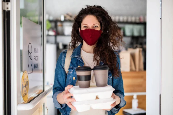 Woman with packed take away food and coffee, looking at camera. Coronavirus concept. — Stock Photo, Image