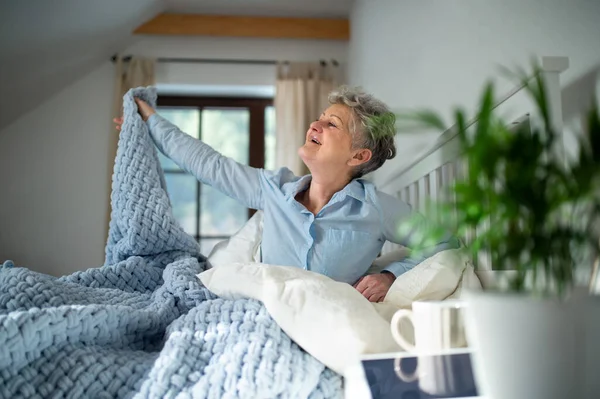 Seniorin zu Hause im Bett, morgens aufstehen, sich dehnen. — Stockfoto